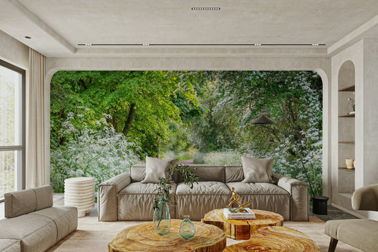 Path of Discovery wallpaper mural with a green spring path and white blossoms behind a beige sofa in a bright living room