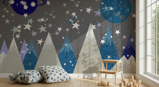 Starry Mountain Dreams wallpaper mural of blue peaks and planets behind geometric floor cushions and a wood step stool