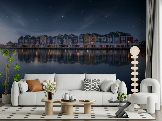 Starry Reflections wallpaper mural of colorful waterfront houses mirrored in calm water under a starry sky behind a white curved sofa in a living room