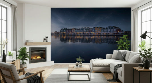 Starry Reflections wallpaper mural of lakeside row houses under a night sky beside a lit fireplace and white sectional in a living room