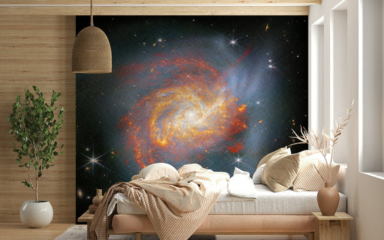 Stellar Canvas wallpaper mural with an orange and blue spiral galaxy above a cream-bedded wood-panel bedroom
