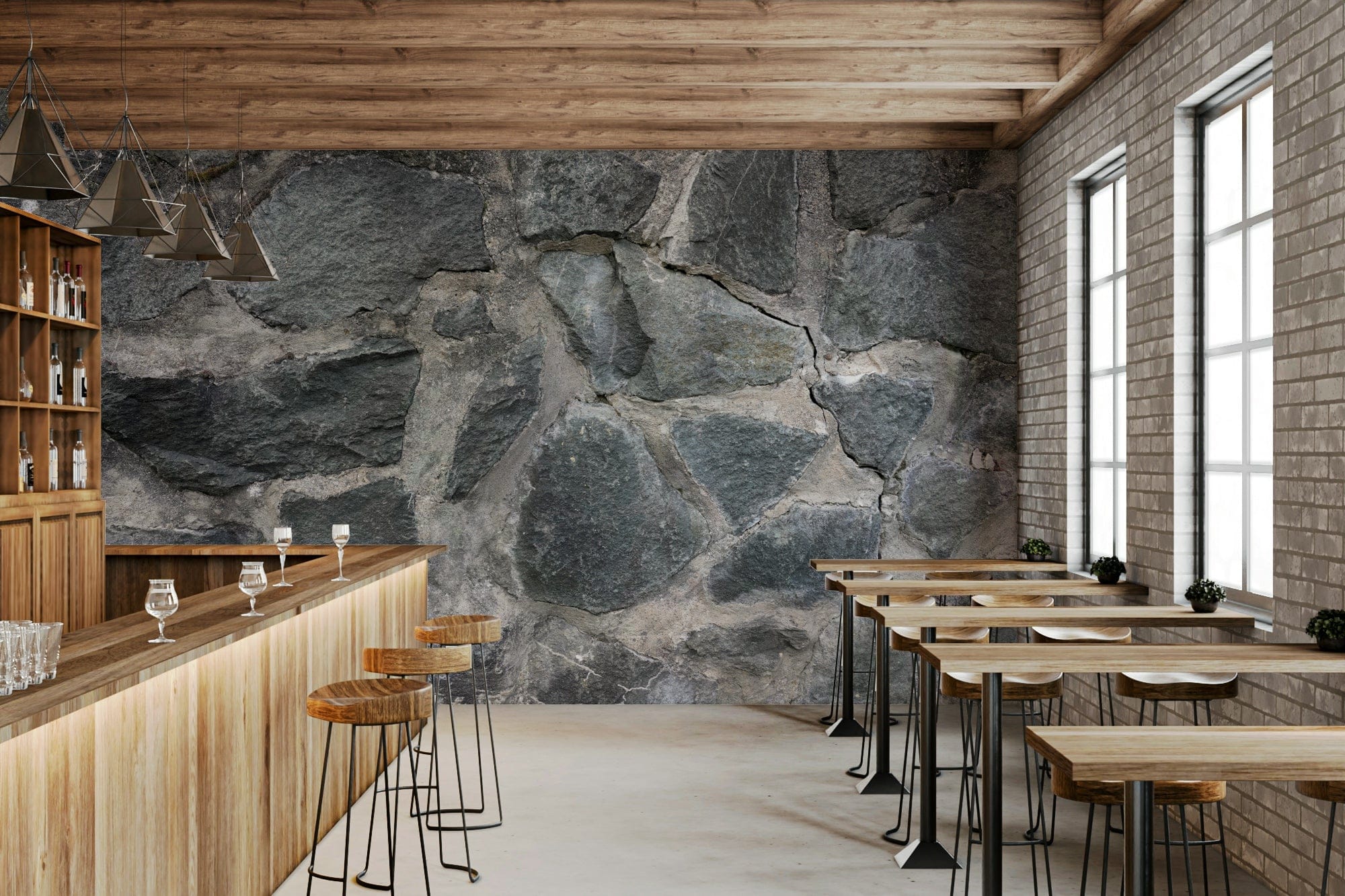 Stone Facade wallpaper mural of grey fieldstone behind a wood bar with stools and black pendant lights