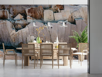 Stone Geometry wallpaper mural of fractured tan rock above a light wood dining table and rattan chairs