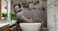 Stone Geometry wallpaper mural of cracked beige and rust rock behind a white freestanding tub in a bright bathroom