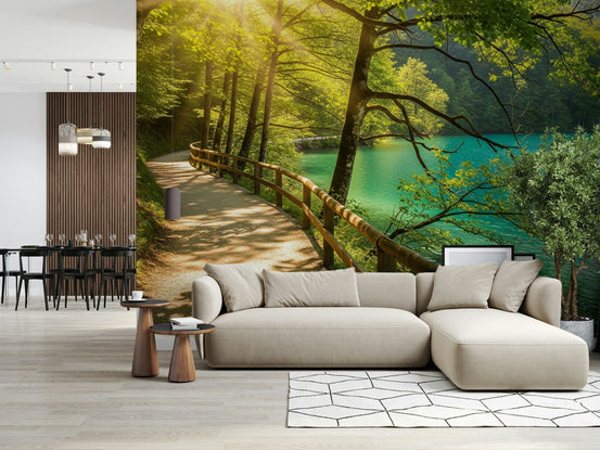 Sunlit Lakeside Path wallpaper mural of a forest trail by a turquoise lake behind a beige sectional sofa in a lounge