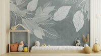 Elegant Teal Botanical Leaf wallpaper mural with white leaves behind a low daybed with plush toys in a kids play room