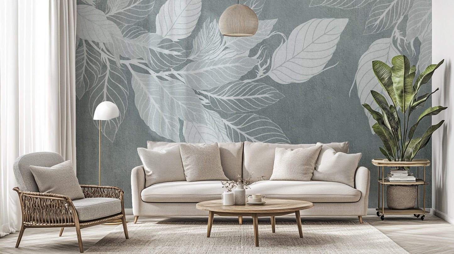 Elegant Teal Botanical Leaf wallpaper mural with pale leaves behind a cream sofa and woven armchair in a living room