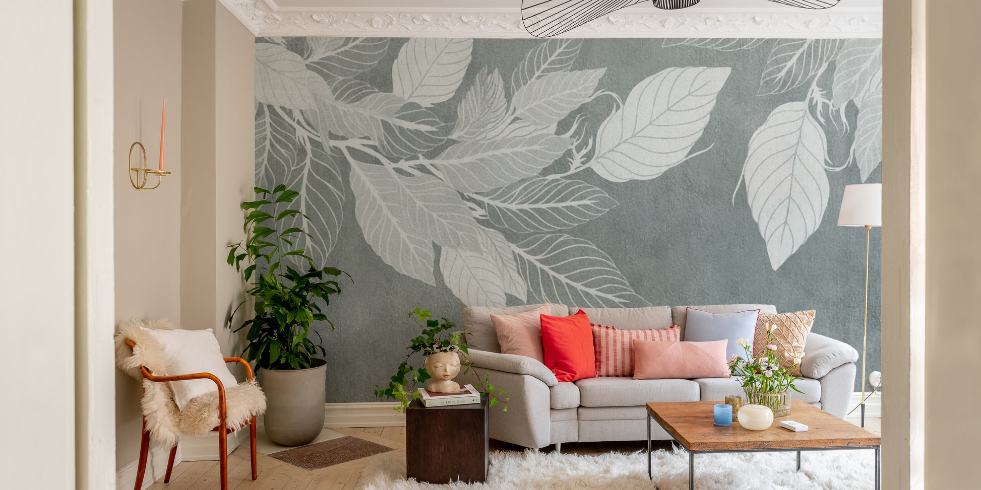 Elegant Teal Botanical Leaf wallpaper mural with white leaves behind a grey sofa with coral pillows in a living room