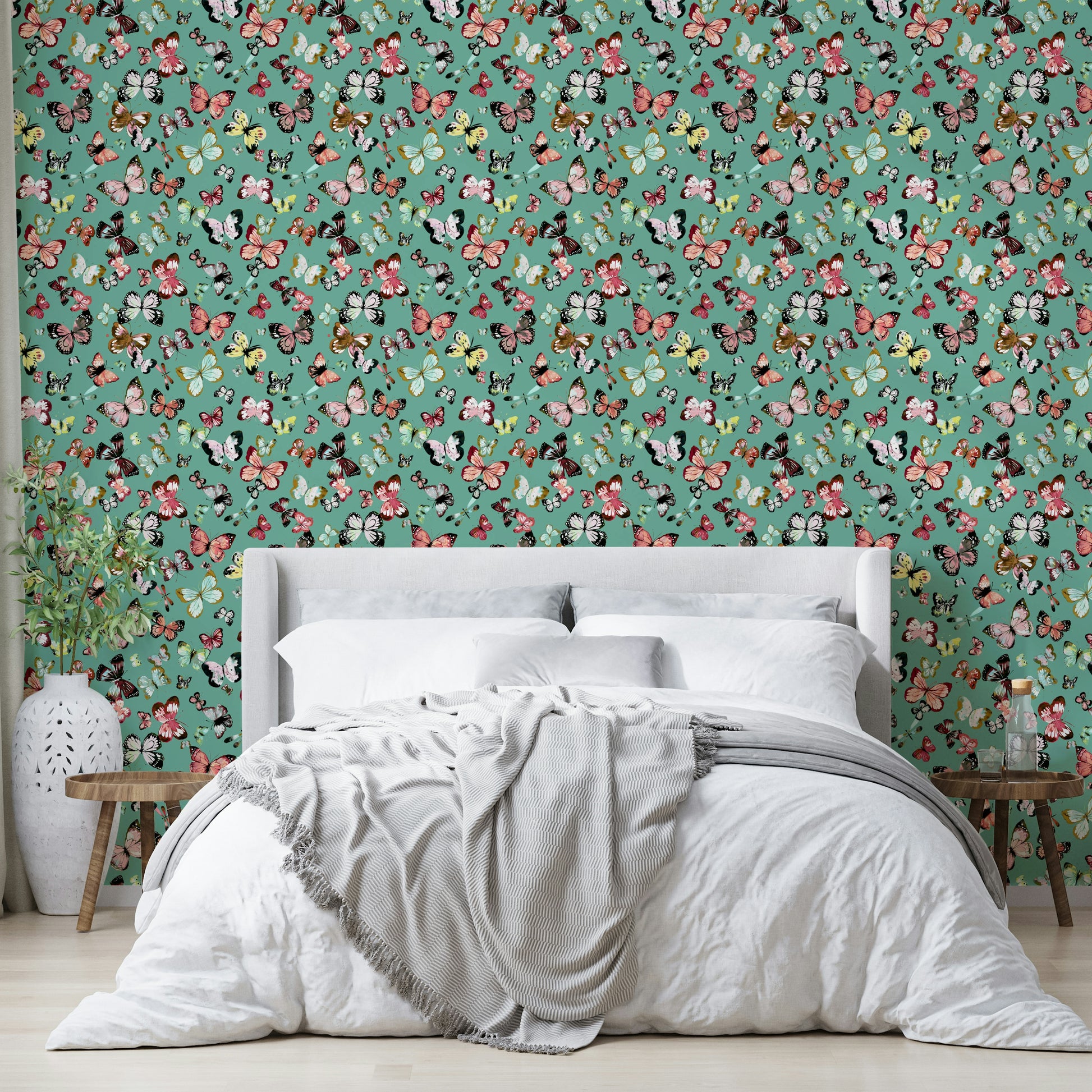 Flying Butterflies Colorful Teal Coral wallpaper behind a white upholstered headboard and grey throw in a bedroom