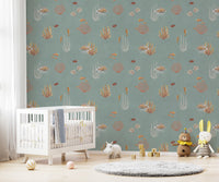Teal Oceanic Wonders wall mural over a white crib with a hippo toy and plush animals in a nursery