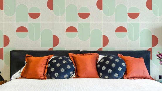 Terracotta & Mint Geometric wallpaper behind a black headboard bed with terracotta and navy pillows