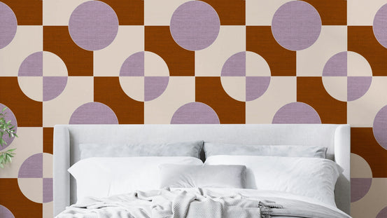 Textured Harmony wallpaper mural in rust and lilac circles behind a grey upholstered bed with white bedding