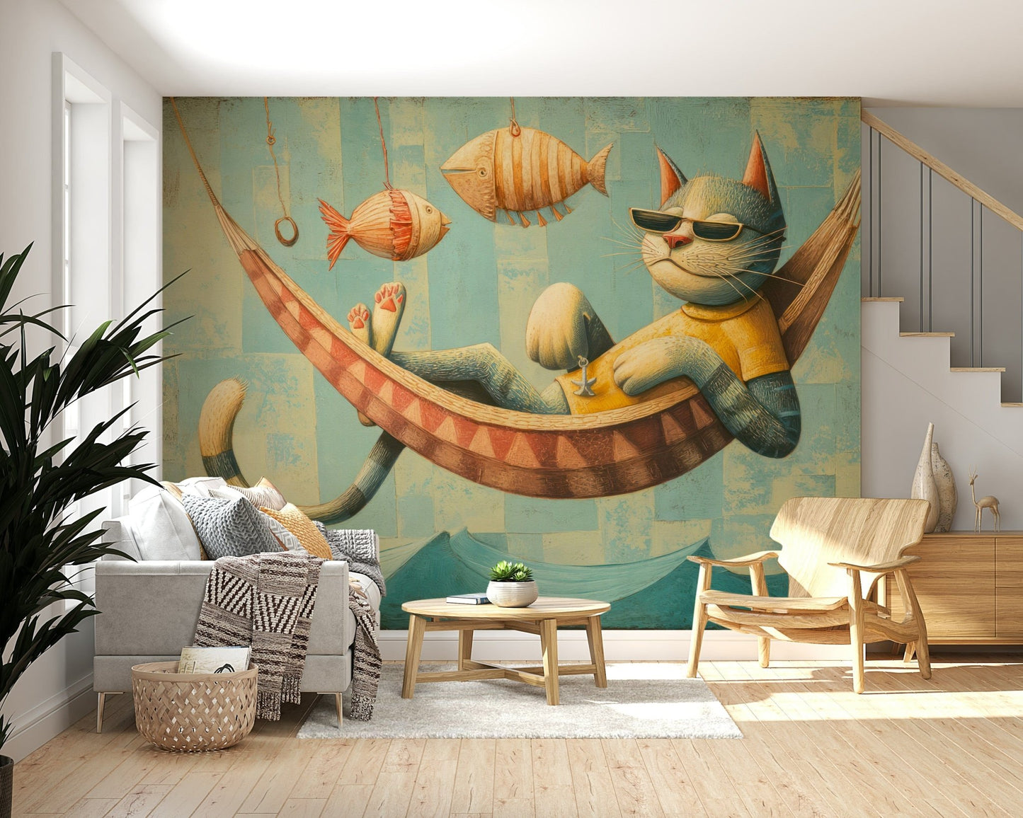 The Cat's Seaside Siesta wallpaper mural above a grey sofa and wood armchair beside a staircase in a living room