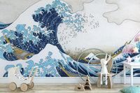 The Great Wave Kanagawa blue ocean wallpaper mural beside a white toy pram and wooden chair in a nursery