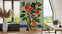 The Keeper of Oranges wallpaper mural of a woman and orange tree beside a wood desk and laptop in a home office