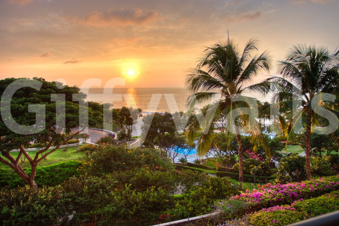Tranquil Hawaii Island Sunset wallpaper mural showing a golden sun setting over the sea with palms and pink blooms