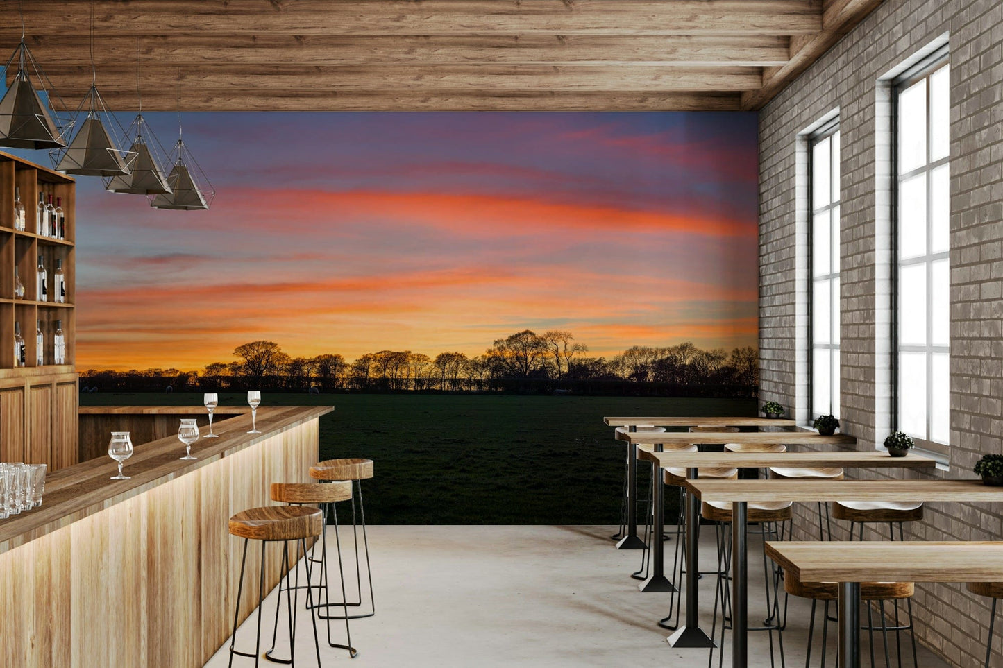 Serenity in Shadows wallpaper mural with sunset field and tree silhouettes behind a wood bar and stools in a cafe