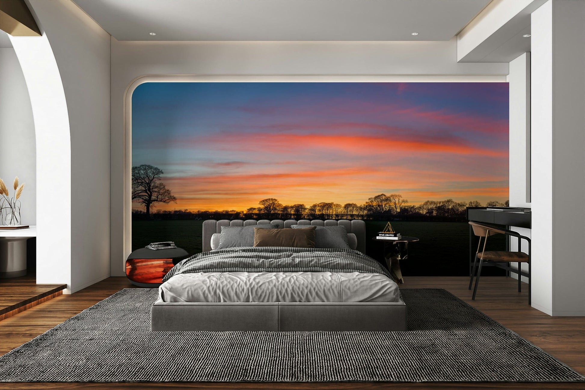 Serenity in Shadows wallpaper mural of an orange sunset over trees behind a grey upholstered bed in a modern bedroom