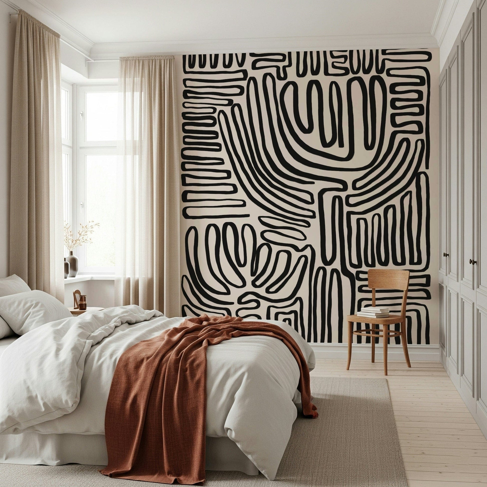 Tribal Echo wallpaper mural with black squiggly lines on cream behind a white bed with a rust throw