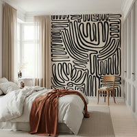 Tribal Echo wallpaper mural with black squiggly lines on cream behind a white bed with a rust throw