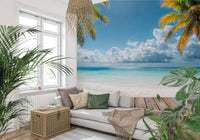 Tropical Beach View wallpaper mural framing a sunny beach behind a white sofa with leafy plants in a bright living room