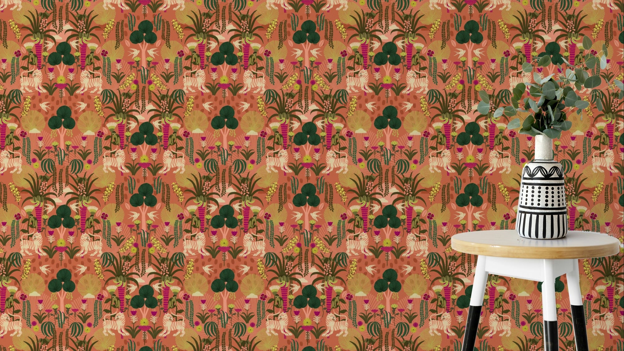 Tropical Tiger Garden wallpaper in terracotta beside a wooden stool with a patterned vase and eucalyptus