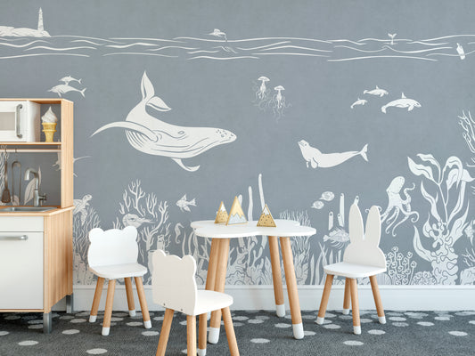 Monochrome Sea Blue wallpaper mural with white line-art whales and coral in a kids room with bear-ear chairs