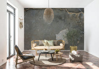 Urban Gray Industrial wallpaper mural in charcoal concrete behind a rattan daybed and olive tree on tile floor