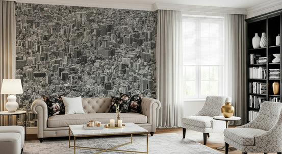 Metropolis Gridlock wallpaper mural of a dense black-and-white aerial cityscape behind a beige Chesterfield sofa and gold accents in a living room