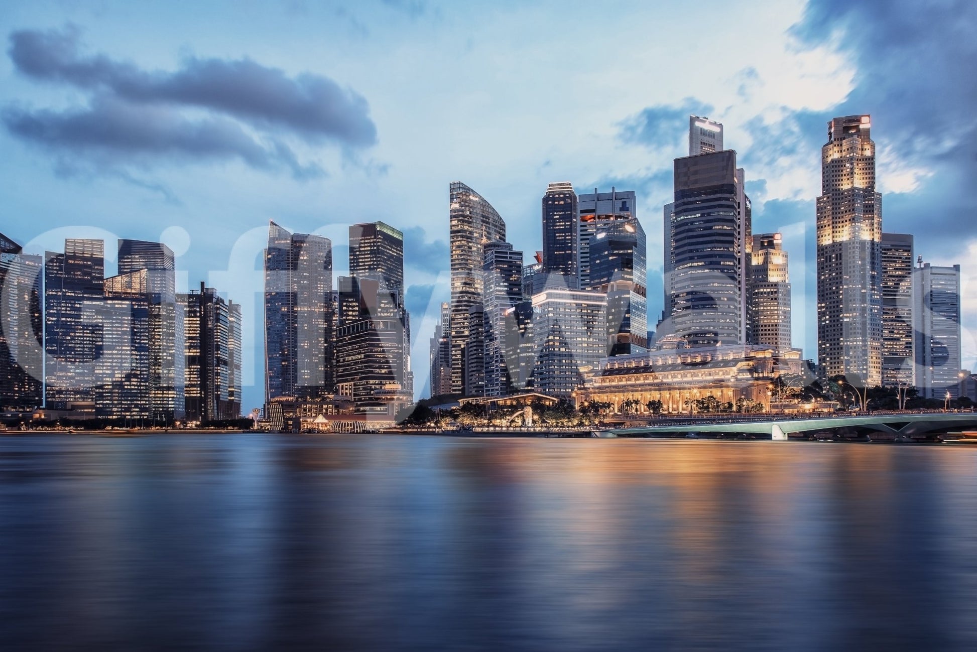 Urban Serenity wallpaper mural shown as a full-wall mural of a waterfront skyline under a blue cloudy sky mirrored in water