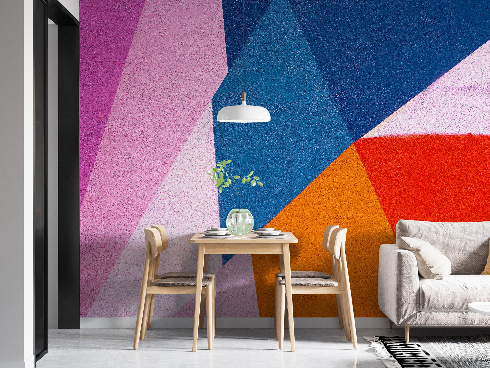 Urban Spectrum Colourful Abstract wallpaper mural in pink, blue and orange behind a small wood dining table and white sofa