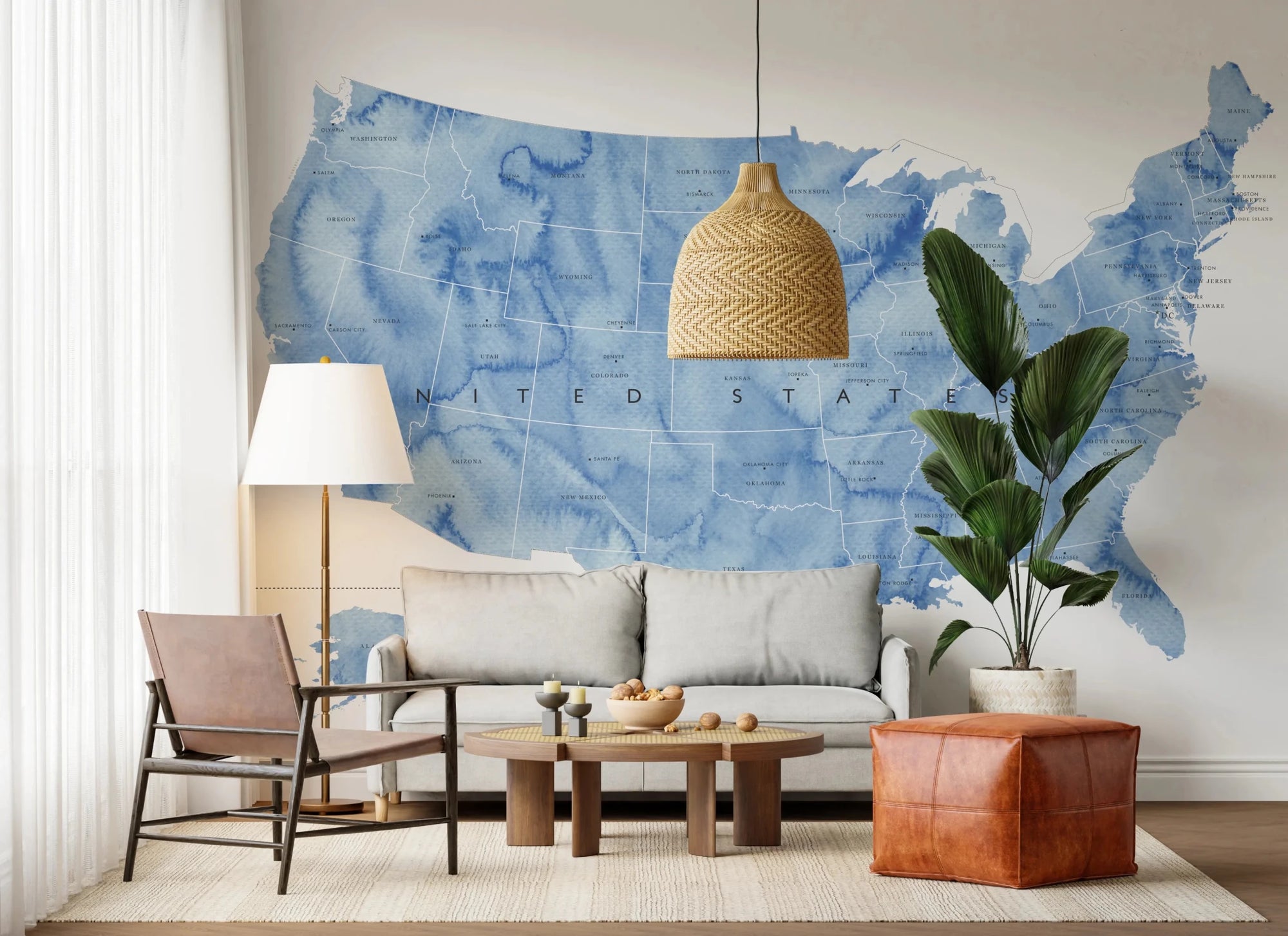 USA map with states and capitals in blue watercolor wallpaper mural behind a grey sofa with a woven pendant light