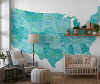 USA map with states and capitals in teal watercolor wallpaper mural in a nursery with a white crib and rocking chair