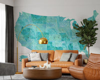 USA map with states and capitals in teal watercolor wallpaper mural over a tan leather sofa with a gold arc lamp