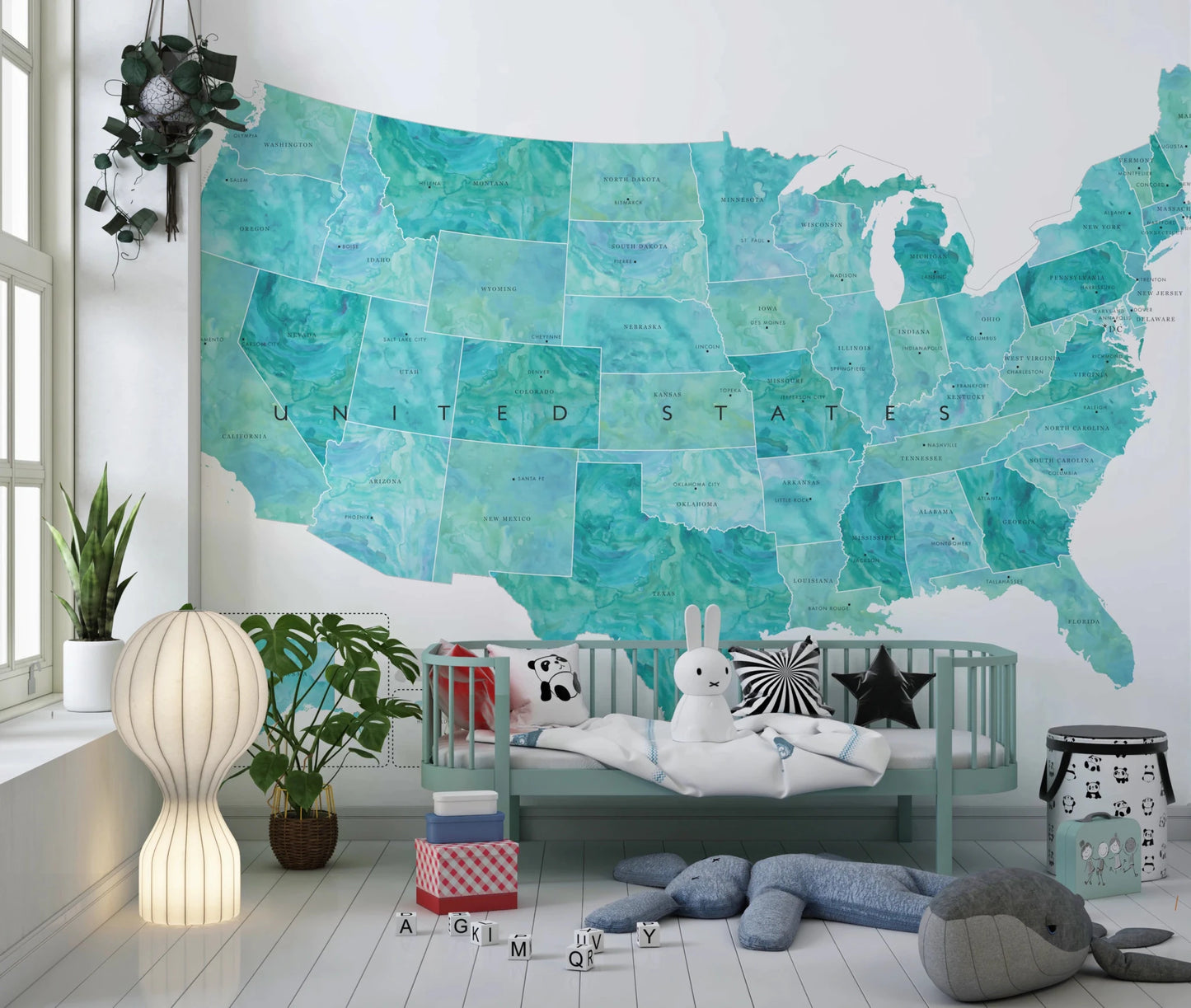 USA map with states and capitals in teal watercolor wallpaper mural in a nursery above a mint green crib