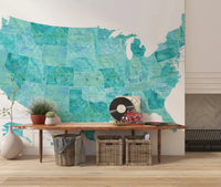 USA map with states and capitals in teal watercolor wallpaper mural above a wood console bench in an entryway