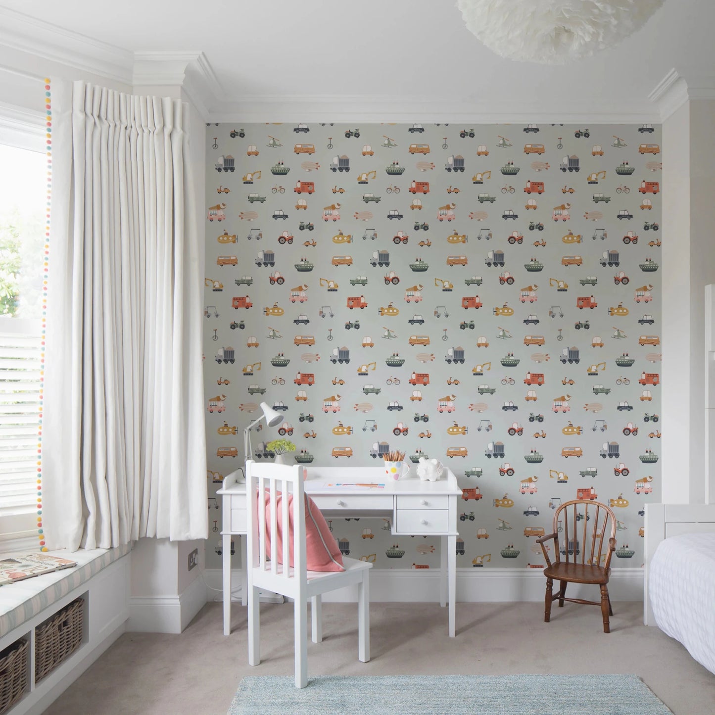 Vehicles in blue background wallpaper above a white desk with red chair in a bright bay-window child's room