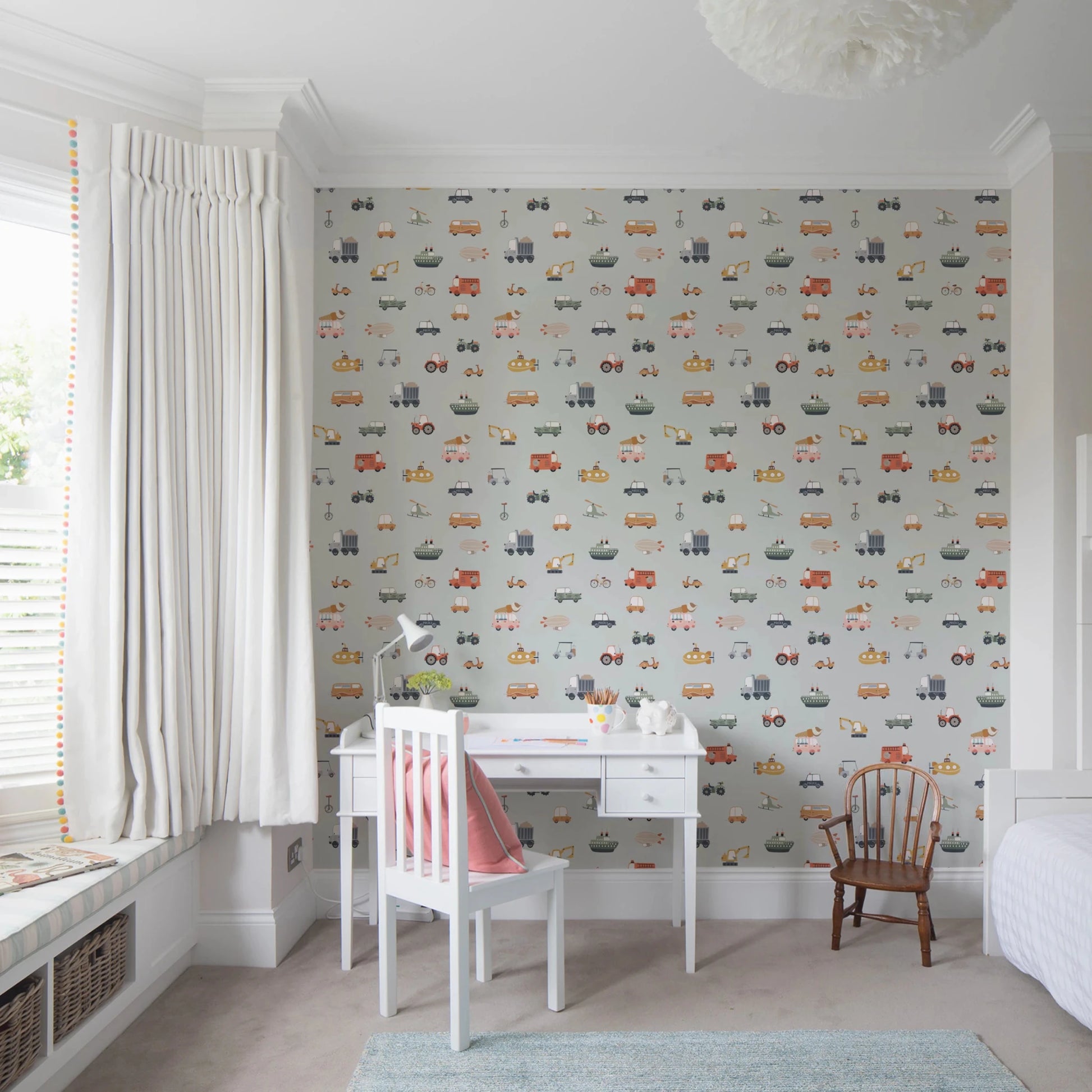 Vehicles in blue background wallpaper above a white desk with red chair in a bright bay-window child's room