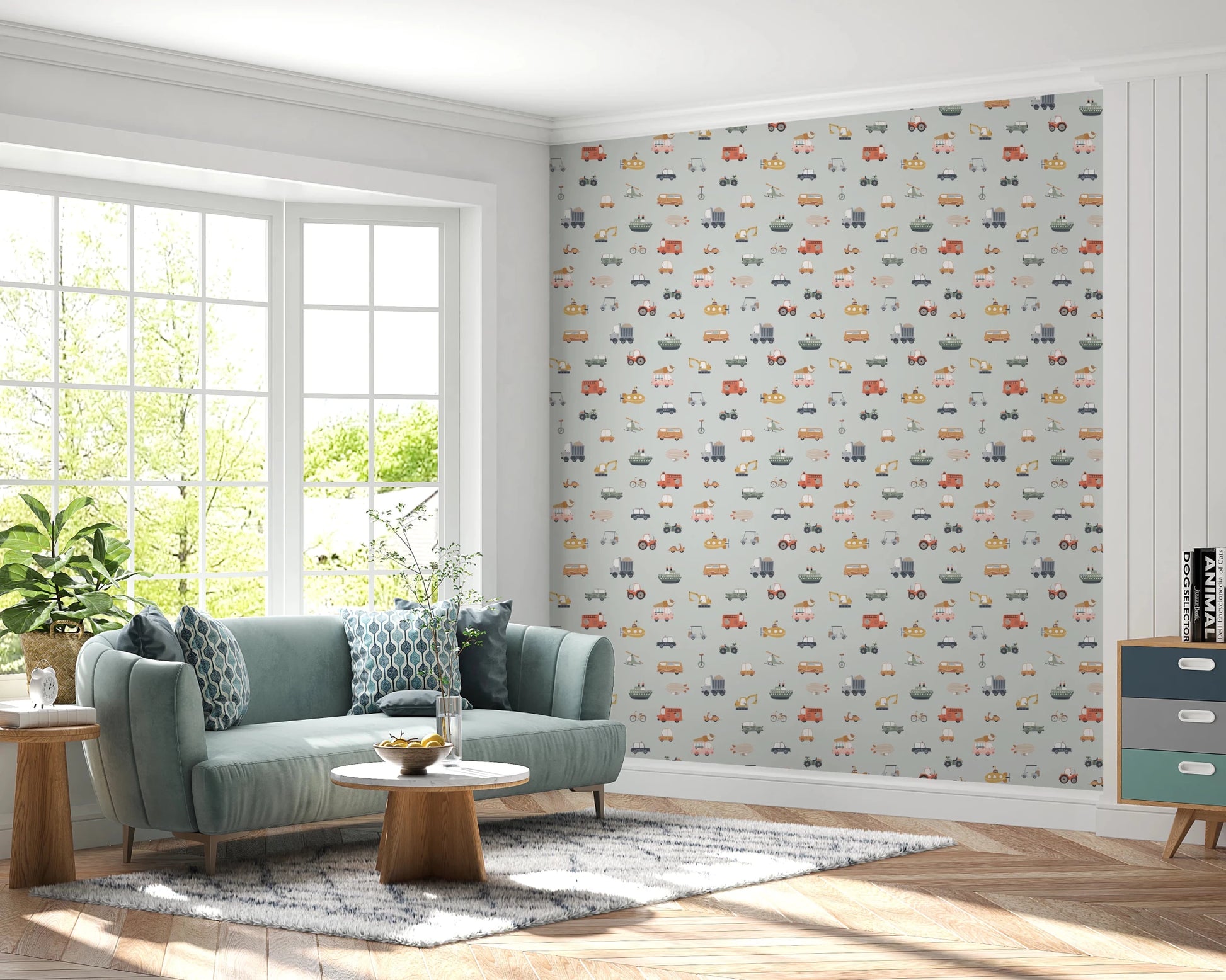 Vehicles in blue background wallpaper behind a green velvet sofa and round wood coffee table in a bright living room