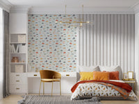 Vehicles in blue background wallpaper above a white desk beside a bed with orange cushions in a child's bedroom