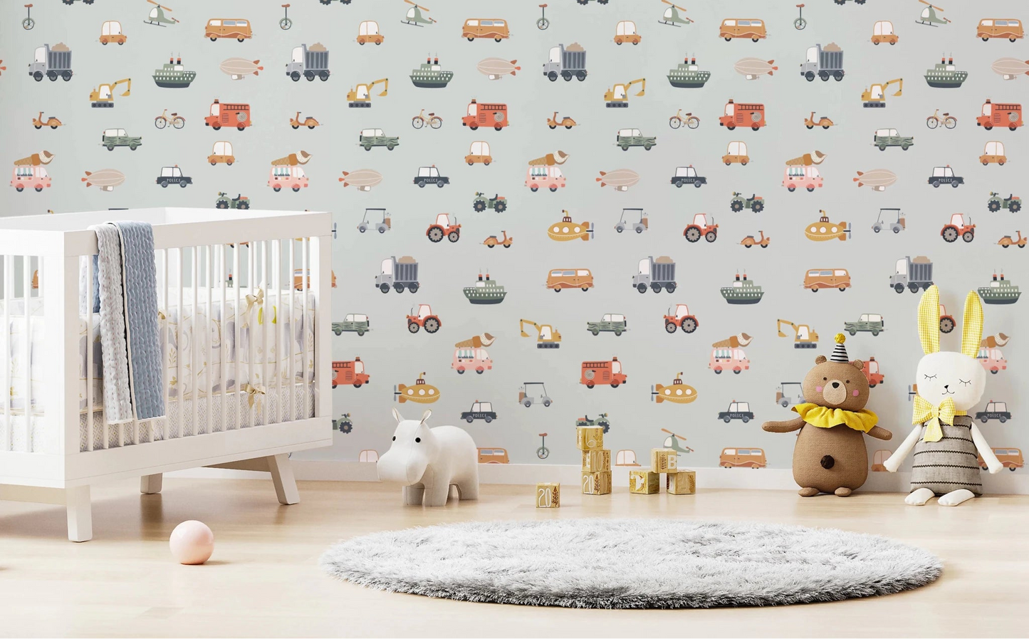 Vehicles in blue background wallpaper with illustrated cars and trucks in a nursery with white crib and plush toys