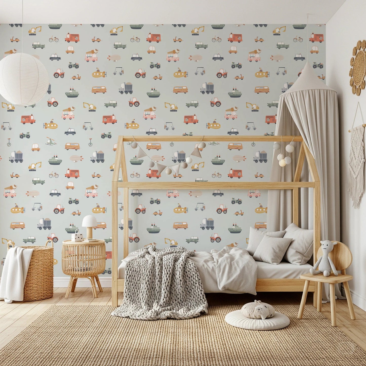 Vehicles in blue background wallpaper behind a wooden house bed with grey knit throw in a kids room