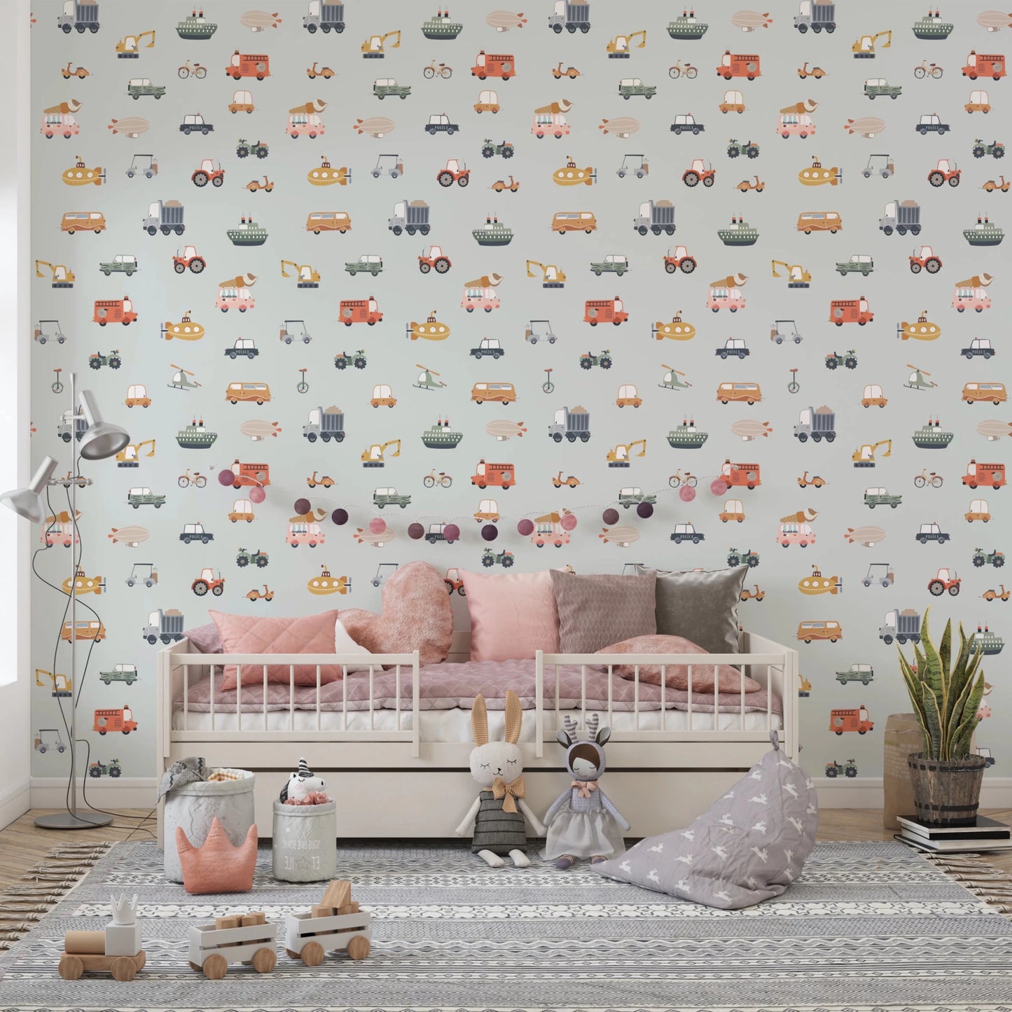 Vehicles in blue background wallpaper behind a pink daybed with plush toys and grey bean bag in a kids room