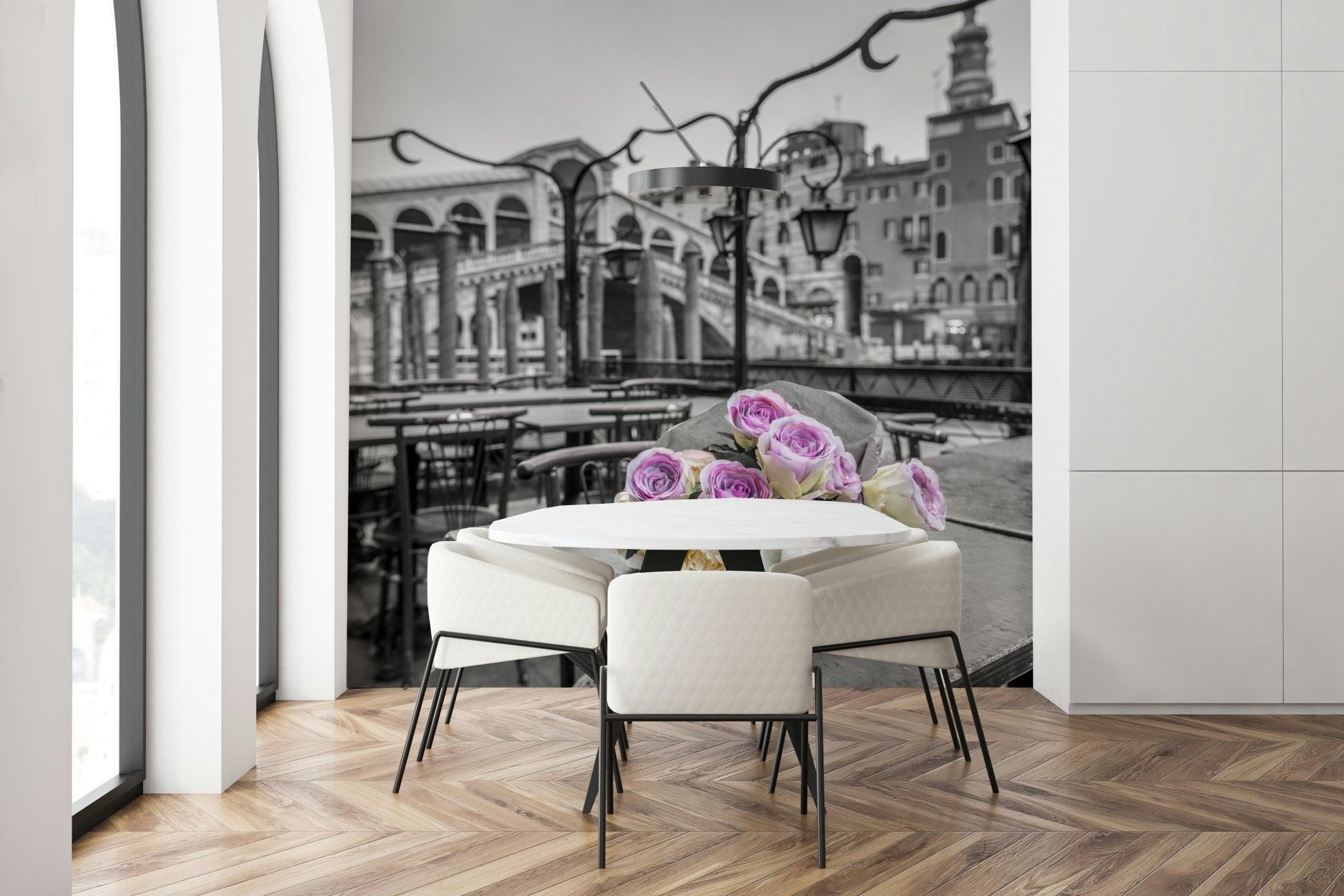 Venetian Blooms wallpaper mural of pink roses on black-and-white Venice canal behind a round white dining table and cream chairs