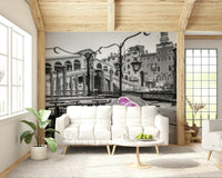 Venetian Blooms wallpaper mural with monochrome Venice bridge and pink roses behind a white sofa and marble coffee table in a living room