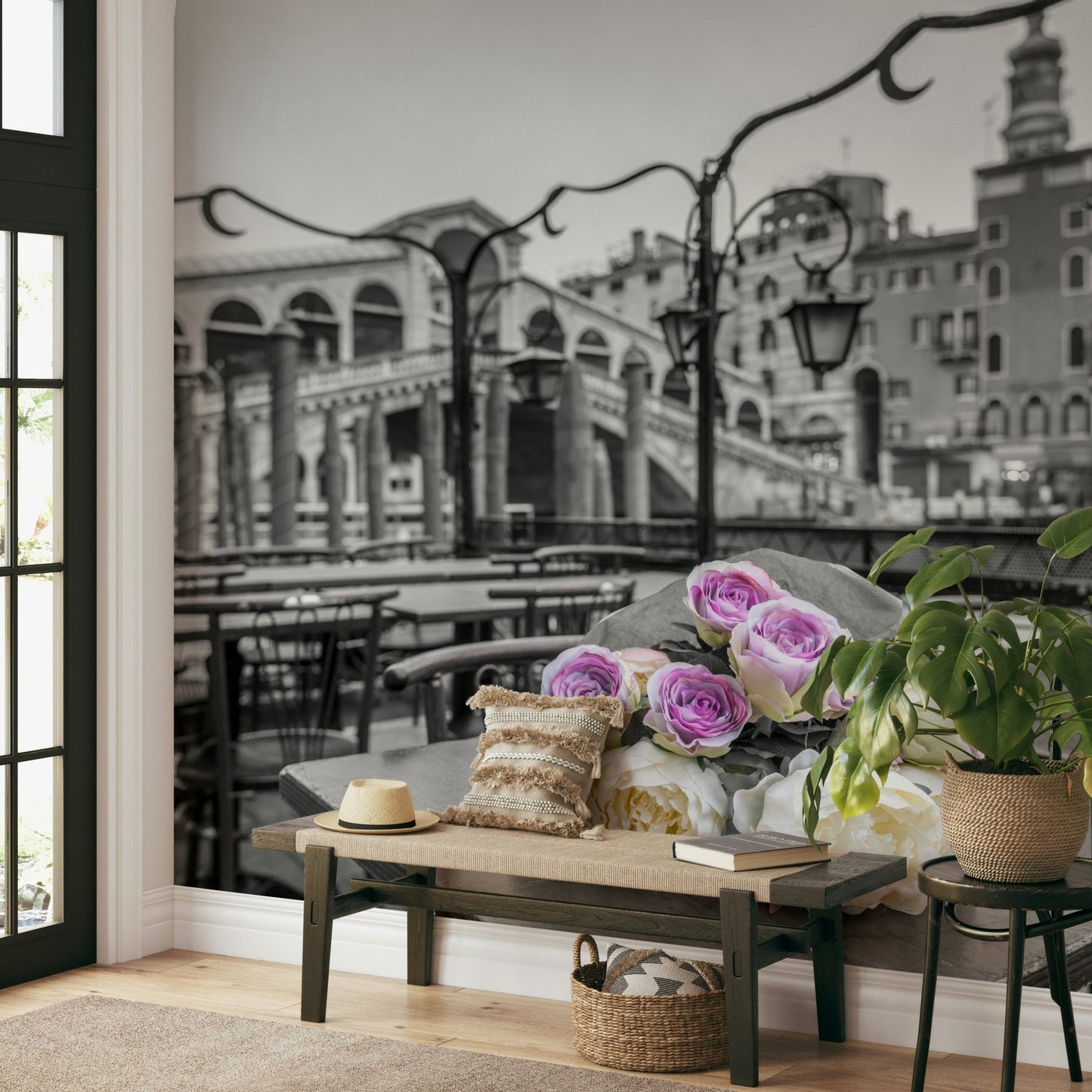 Venetian Blooms wallpaper mural with grey Venice bridge and roses behind a wooden entryway bench, sun hat and potted plant