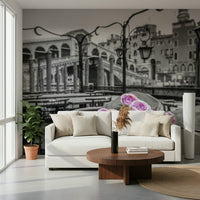 Venetian Blooms wallpaper mural showing pink roses over monochrome Venice behind a cream sofa and round wood coffee table