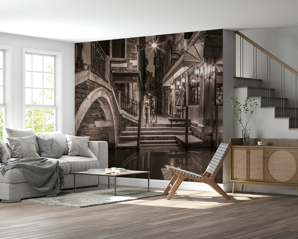 Venetian Canals wallpaper mural of a sepia Venice canal bridge behind a grey sofa beside a wood staircase and sideboard