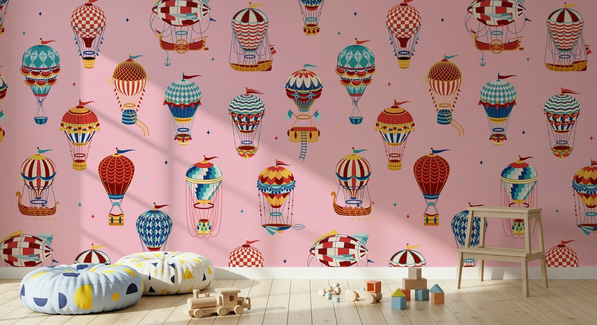 Vintage Balloon Voyage wallpaper mural of patterned balloons on pink behind confetti floor cushions and a wood train toy