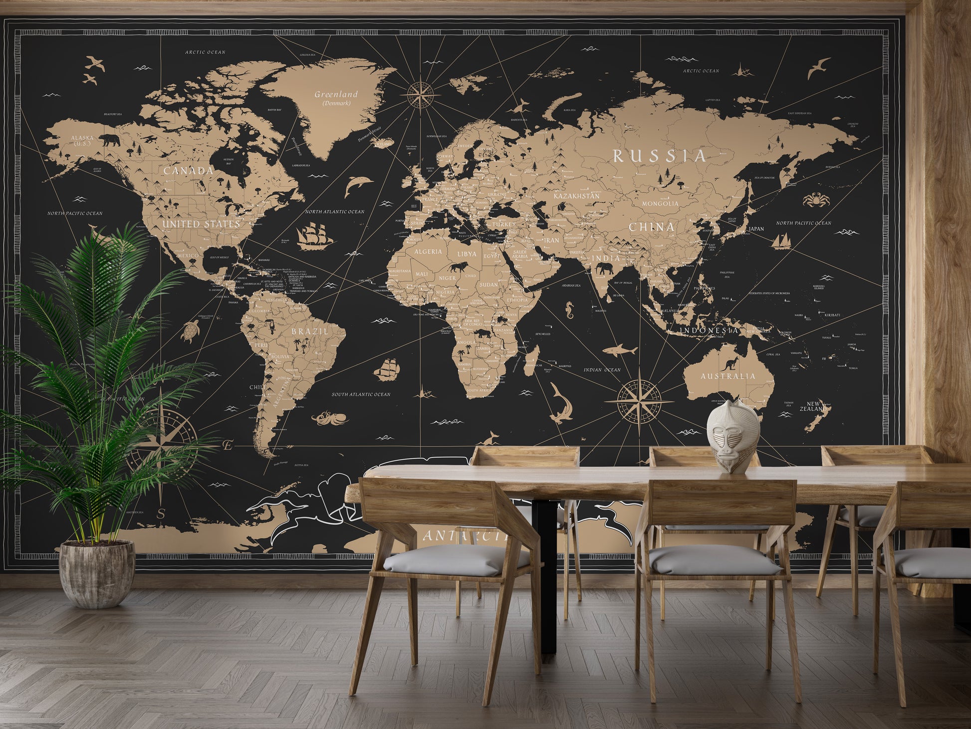 Vintage Black Golden World Map wallpaper mural in gold tones behind a wooden dining table and chairs with a palm plant